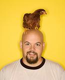 Bald man  with chicken on his head.
