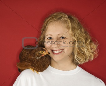 Caucasian woman with chicken on shoulder.