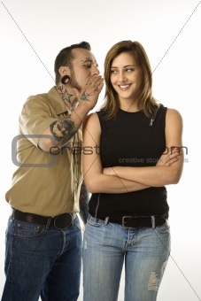 Caucasian male whispering into ear of teen female.
