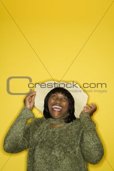 Adult female holding floppy hat.