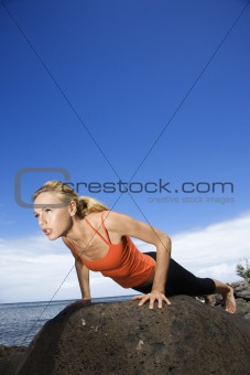 Woman doing push up on rock.