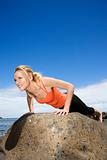 Woman doing push up on rock.