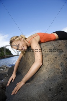 Woman draped over large rock.