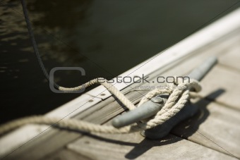 Rope tied to cleat on boat dock.