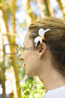 Woman wearing plumeria flower behind ear.