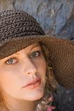 Young Caucasian female portrait wearing hat beside rock.
