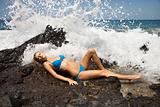 Young adult female in bikini with wave crashing.