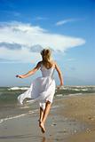 Pre-teenage girl running down the beach. 