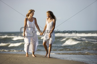 Mother and daughter walking down beach.
