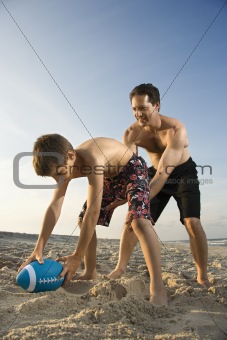 Boy hiking football to his dad.