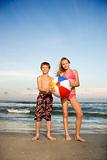 Boy and girl holding beachball on beach.