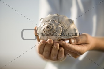 Boy holding seashell.