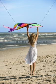 Girl holding kite on beach.