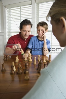Dad teaching chess to son.