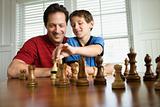 Dad teaching chess to son.