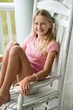 Girl sitting in rocking chair on porch.