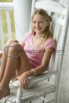 Girl sitting in rocking chair on porch.