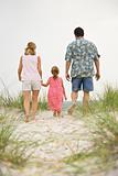 Mom, Dad and daughter walking toward beach.