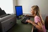 Pre-teen girl looking at computer screen.
