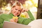 Beautiful, Smiling Woman Enjoys Her Warm Drink and Laptop Relaxing Day.