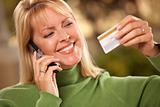 Cheerful Smiling Woman Using Her Phone with Credit Card in Hand.