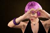 Portrait of woman with shiny purple hair making heart shape