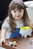 cute little girl painting piggy bank