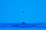 blue droplet hitting the water surface splashing it up