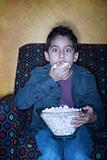 Young Hispanic boy with popcorn watching television