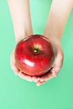 shot of child holding a red apple on green background vertical