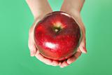 shot of a child holding a red apple on green background