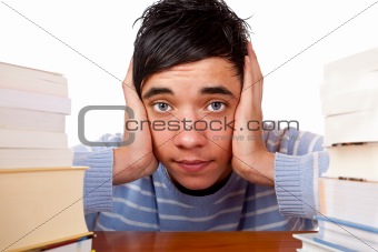 Young handsome male student sitting frustrated between study boo