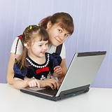 Mother and daughter playing with a computer at home