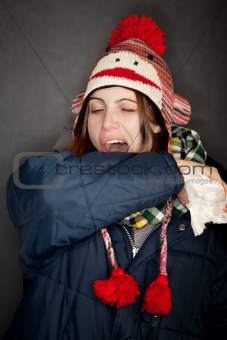 Pretty young woman sneezing into her arm