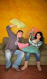 Hispanic couple on couch play fighting with pillows