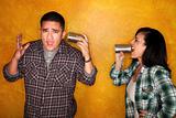 Attractive Hispanic man and woman communicate through tin cans