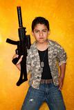 Handsome young Hispanic in front of yellow wall with toy gun