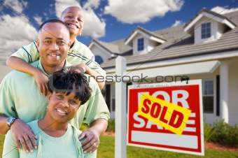 Happy and Attractive African American Family with Sold For Sale Real Estate Sign and House.