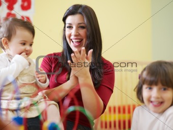 two little girls and female teacher in kindergarten
