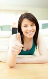 Positive woman with thumbs up lying on the floor