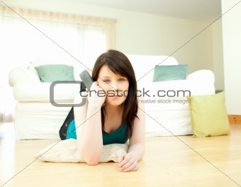 Concentrated woman watching television lying down on the floor