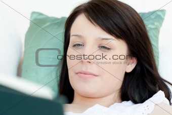 Portrait of a smiling teen girl studying lying on a bed against a white background