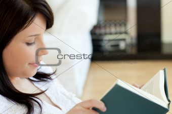 Portrait of a smiling teen girl studying lying on a bed against a white background