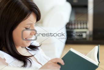 Attractive woman reading a book lying on a sofa 