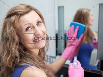 Charming woman cleaning a bathroom's mirror 