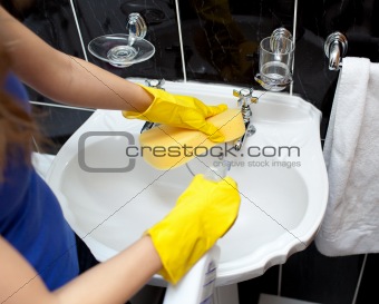 Young woman cleaning a bathroom's sink 