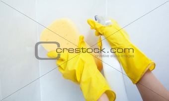 Close-up of a woman cleaning with a sponge and detergent spray
