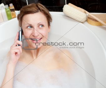 Radiant woman talking on phone in a bubble bath 