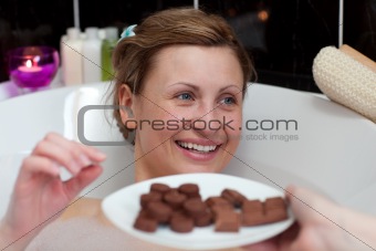 Bright woman eating chocolate while having a bath 