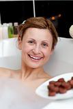 Radiant woman eating chocolate while having a bath 